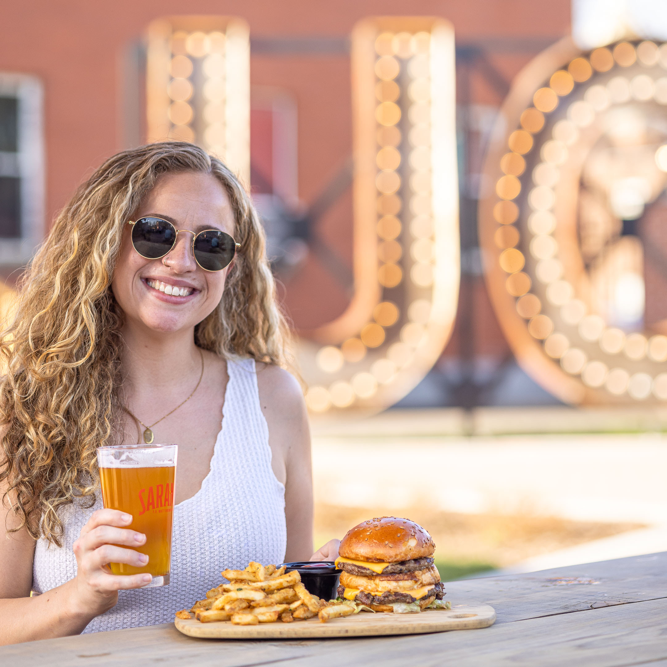 Women with Saranac pint and burger at the 1888 Biergarten restaurant.
